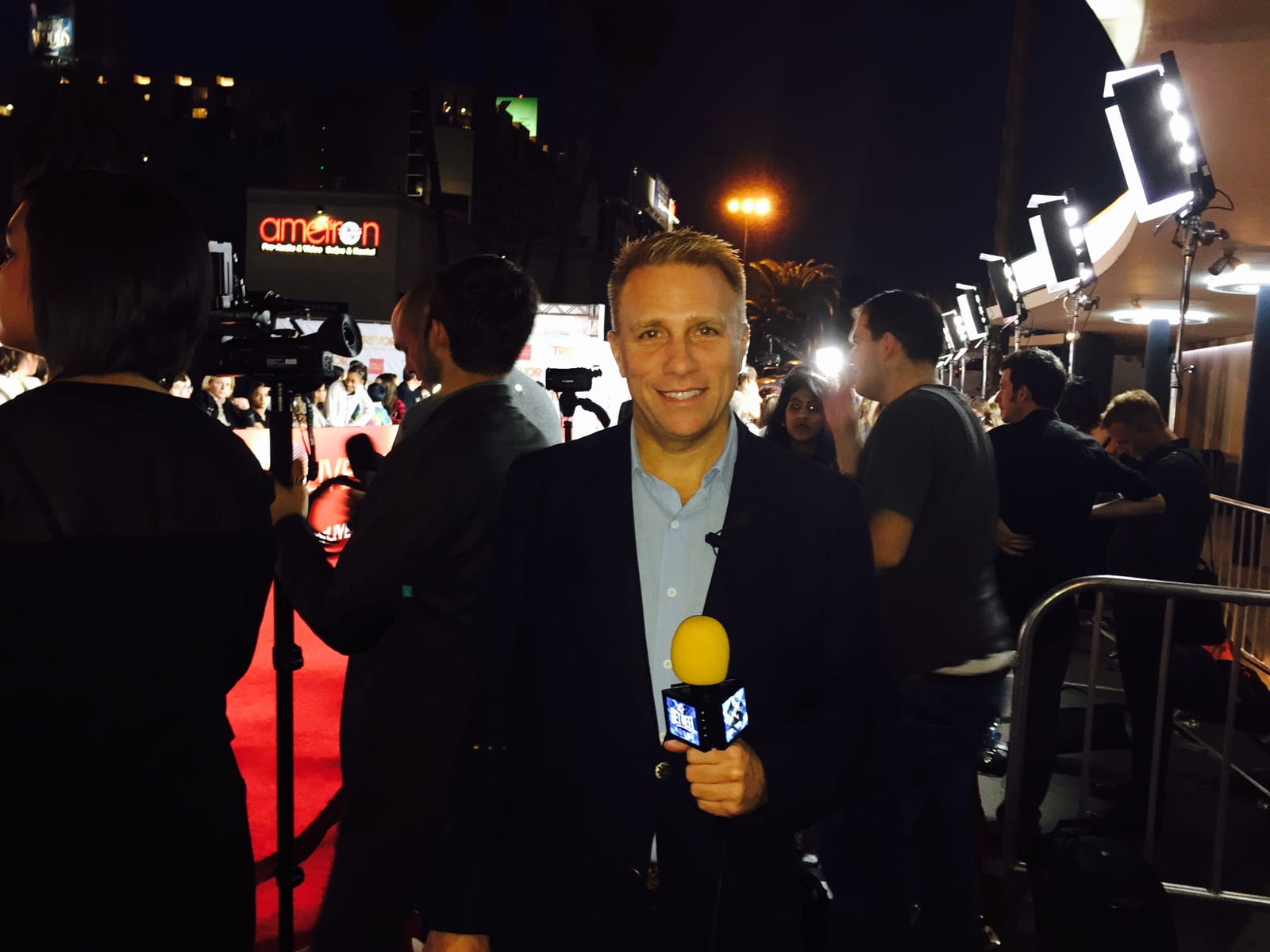 Cary Harrison reporting from a red-carpet event, camera crew and lights behind him
